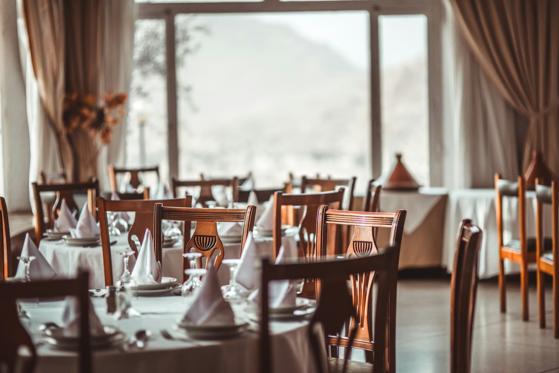 Salle du restaurant Héra, tables dressées et lumière chaude